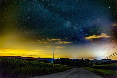 Road amidst field against sky at night