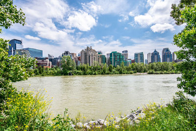 Scenic view of river by buildings against sky