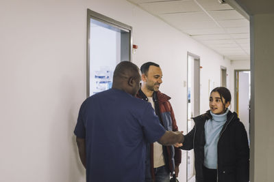 Doctor doing handshake with girl standing at hospital