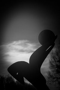 Low angle view of silhouette sculpture against sky at sunset