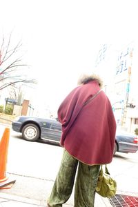 Rear view of woman standing on road in city