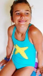 Portrait of smiling girl sitting against wall