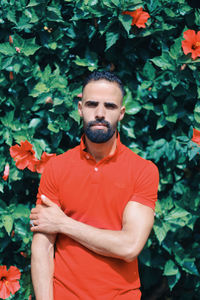 Portrait of young man standing against plants during sunny day