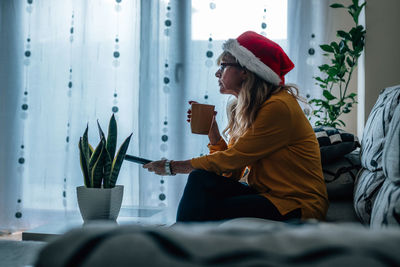 Portrait of young woman using mobile phone while sitting on bed