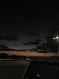 Cars on illuminated street against sky at night