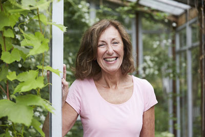 Portrait of happy senior gardener standing at entrance in yard