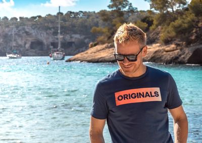 Man wearing sunglasses standing by sea