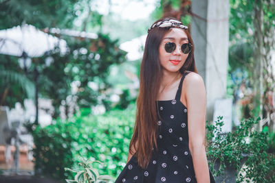 Smiling young woman wearing sunglasses looking away