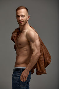 Portrait of shirtless man standing against white background