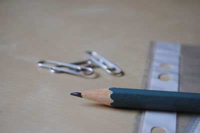 Close-up of pencil and paper clips on table in office