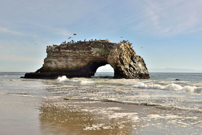 Rock formation on beach against sky