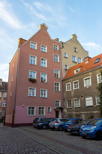 Cars parked on road by buildings against sky