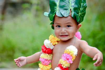 Portrait of cute boy wearing leaves and garland standing outdoors