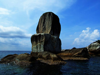 Rock formation in sea against sky