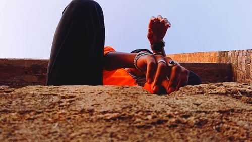Man sitting on rock against clear sky