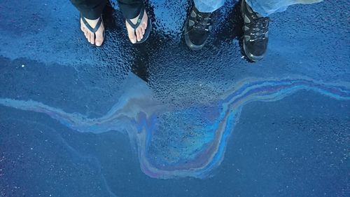 Low section of man standing on puddle