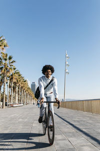 Mid adult man riding bicykle on a beach promenade, listening music