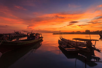 Boats moored in sea against sky during sunset