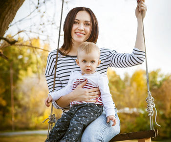 Mother and daughter sitting on swing outdoors