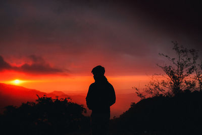 Silhouette man standing on field against sky during sunset