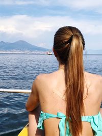 Rear view of young woman in sea against sky