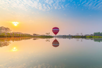 Hot air balloon in lake against sky during sunset