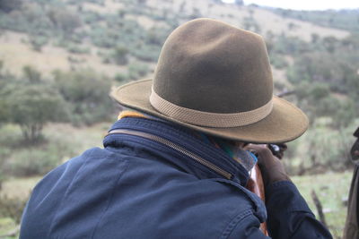 Rear view of hunter sitting on field