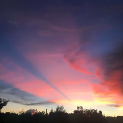 Low angle view of silhouette trees against dramatic sky