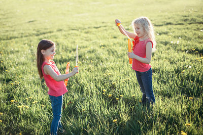 Soap bubbles game. girls friends blowing soap bubbles in park on summer day. kids having fun 