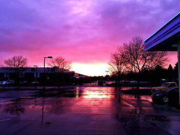 Cars on street against cloudy sky at sunset