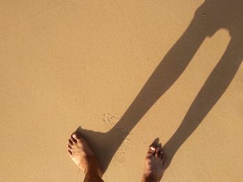 Low section of man standing on sand at beach