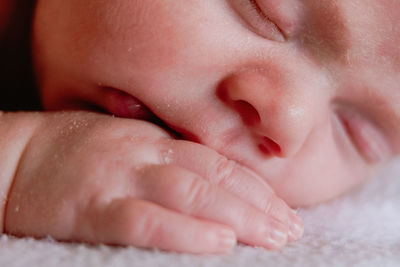 Close-up of baby girl lying on bed