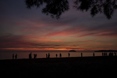 Silhouette people on beach against sky during sunset