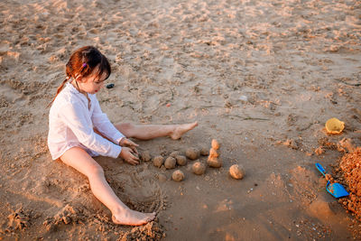 High angle view of girl playing on sand at beach