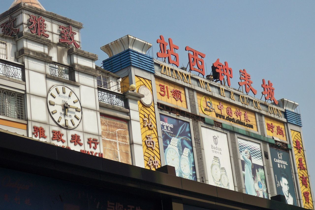 low angle view, text, built structure, communication, architecture, no people, building exterior, western script, sky, day, commercial sign, outdoors, advertisement, clear sky, human representation, script, sign, capital letter, non-western script, building