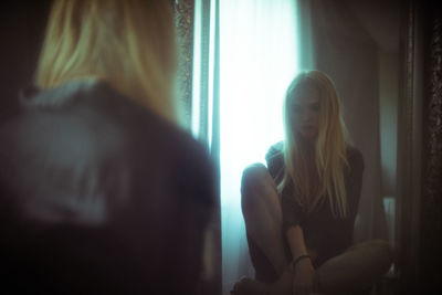 Sad woman sitting in front of mirror at home