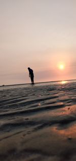 Silhouette man on beach against sky during sunset