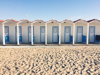 Huts at beach against sky on sunny day