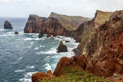 Scenic view of sea by cliff against sky