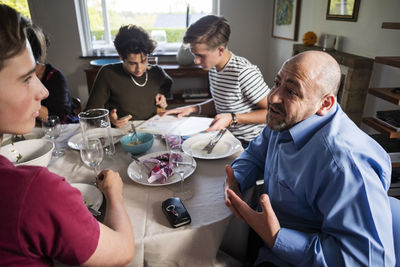 Friends and family talking at dining table in dinner party