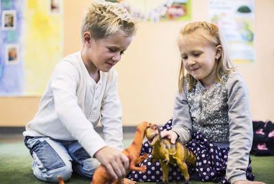 Kids playing with toy dinosaurs in kindergarten