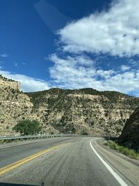 Road by mountains against sky