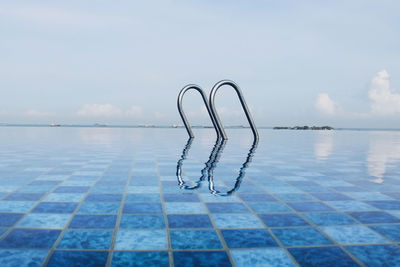 Swimming pool by sea against sky