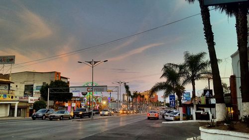 Cars on road against sky during sunset