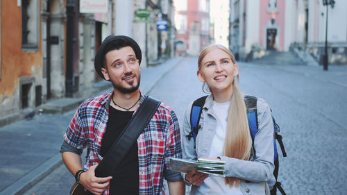 Man and woman holding map on footpath in city