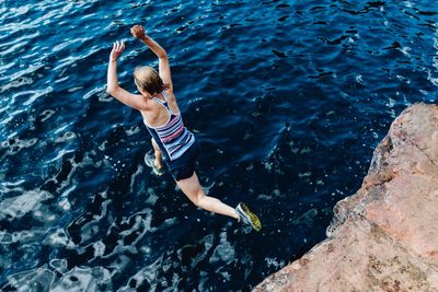 High angle view of woman jumping into the sea