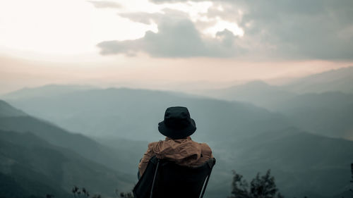 Rear view of man looking at landscape during sunset