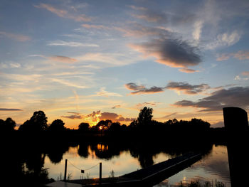 Silhouette trees by lake against sky during sunset