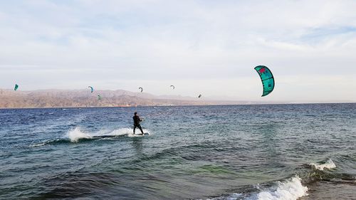 Man windsurfing in sea against sky