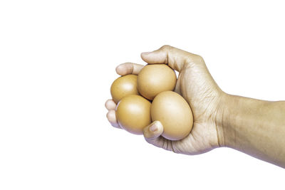 Close-up of hand holding eggs against white background